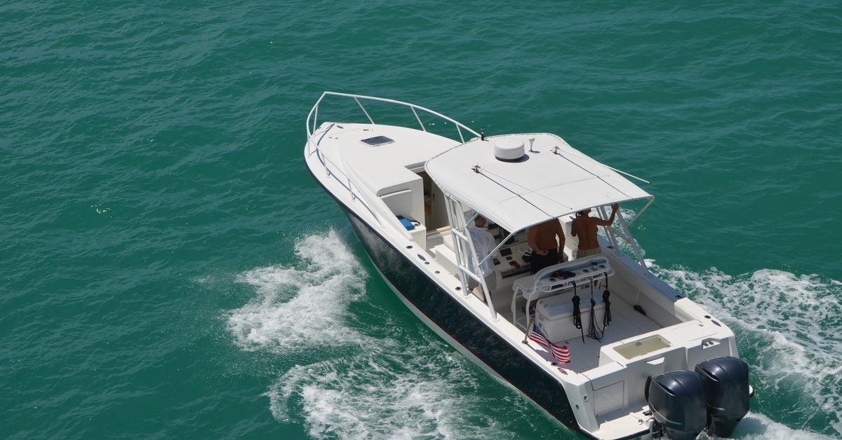An overhead view of a fishing boat with an awning and American flag sailing over the water during the day.