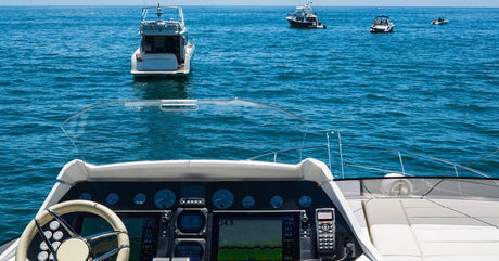 A first-person view of the console in a boat with the ocean in front and various electronic gadgets and equipment onboard.