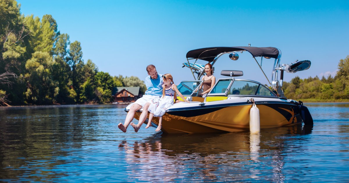 A dad and his daughter sitting on the bow of a boat. The mother of the family is slowing driving the boat through the water.