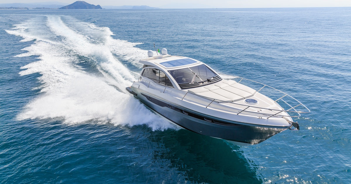 A white and blue speed boat riding over the water, while producing a large wake behind it.