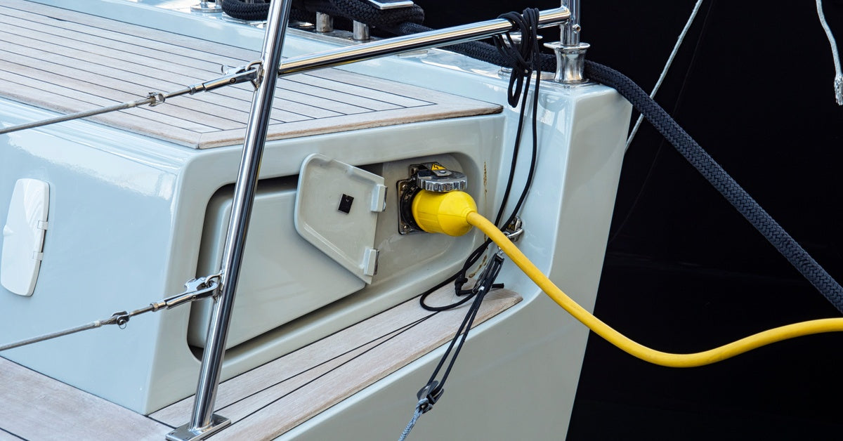 The back end of a boat featuring a battery charging port. A large yellow cable is plugged into the port to charge the battery.