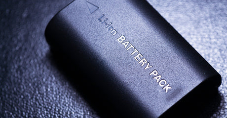 A black lithium-ion battery pack with a small arrow indicating the correct side with the connector sitting on a black background.