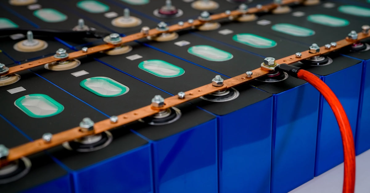 Several rows of connected electric lithium batteries connected vita metal pieces on their silver bolts with one wire.