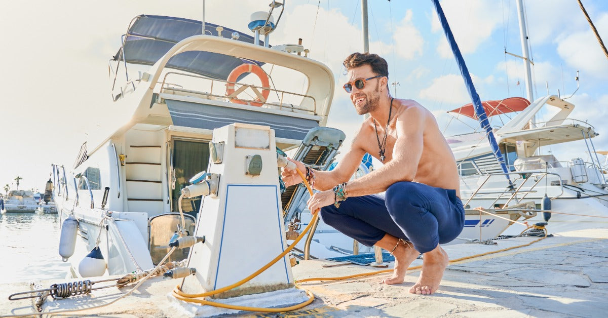 A person crouching down by a marine charging station and investigating the cord that leads to their boat.