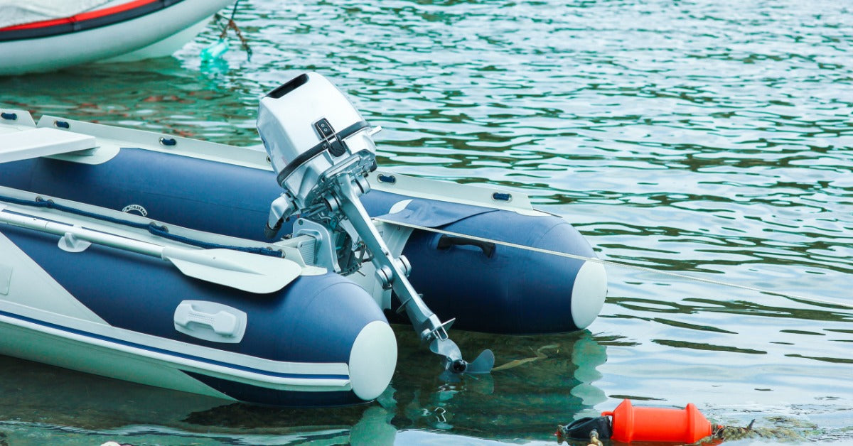 A blue-and-white boat with a silver trolling motor currently docked alongside other vessels in calm waters.